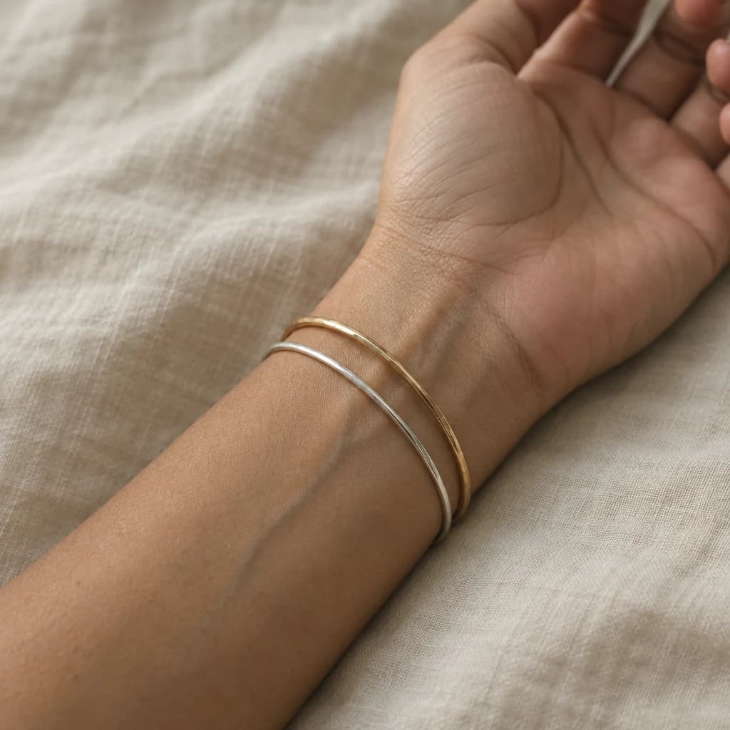 Muñeca con una pulsera dorada y una plateada, con luz de ventana: así se comparan el oro y la plata